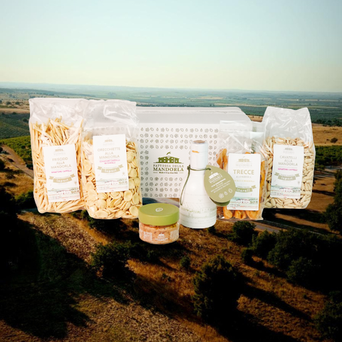 Confezione regalo gourmet con prodotti alla mandorla pugliese su tavolo in legno