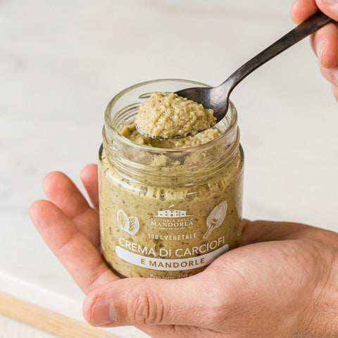 CREMA DI CARCIOFI E MANDORLA BIO - 220g — vasetto aperto in mano con cucchiaio