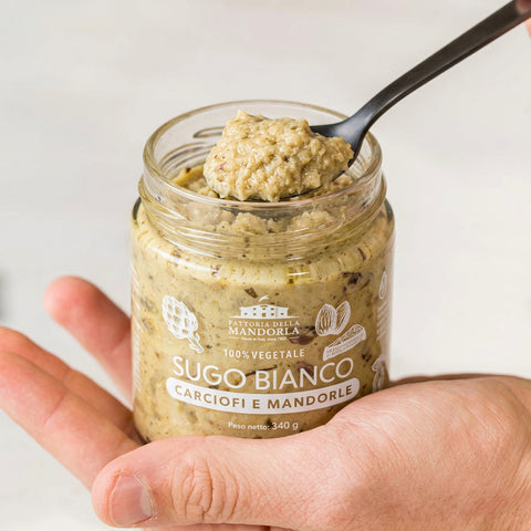 SUGO BIANCO DI CARCIOFI E MANDORLA BIO - 340g — vasetto aperto in mano con cucchiaio